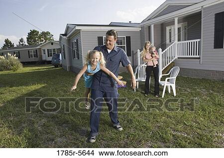 Portrait of a man playing with his blue-collar family in front of a trailer home View Large Photo Image Picture - Portrait of a man playing with his blue-collar family in front of a trailer home. Fotosearch