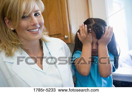 Stock Image - Portrait of a mother with her daughter playfully covering her eyes. Fotosearch