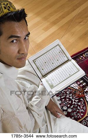 Portrait of a Muslim man reading Koran on a prayer mat View Large Photo Image Picture - Portrait of a Muslim man reading Koran on a prayer mat. Fotosearch