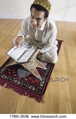 Portrait of a Muslim man reading Koran on a prayer mat View Large Photo Image Stock Photograph - Portrait of a Muslim man reading Koran on a prayer mat. Fotosearch