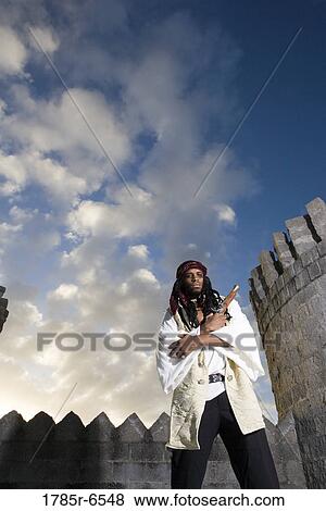 Portrait of a pirate armed with a pistol with castle turrets and parapets in the background View Large Photo Image Stock Photo - Portrait of a pirate armed with a pistol with castle turrets and parapets in the background. Fotosearch