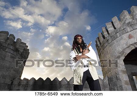 Portrait of a pirate armed with a pistol with castle turrets and parapets in the background View Large Photo Image Stock Photo - Portrait of a pirate armed with a pistol with castle turrets and parapets in the background. Fotosearch