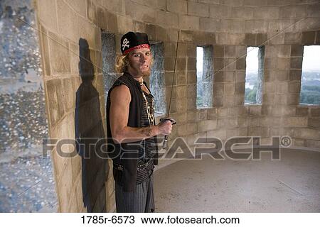 Stock Image - Portrait of a pirate armed with a sword inside a castle turret. Fotosearch