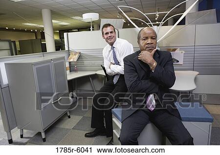 Portrait of a serious manager thinking while younger office worker smiles behind View Large Photo Image Stock Image - Portrait of a serious manager thinking while younger office worker smiles behind. Fotosearch