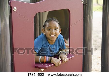 Portrait of a smiling girl looking through an opening at a playground View Large Photo Image Stock Image - Portrait of a smiling girl looking through an opening at a playground. Fotosearch