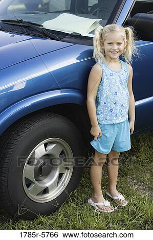 Portrait of a smiling girl standing by a car View Large Photo Image Stock Photograph - Portrait of a smiling girl standing by a car. Fotosearch