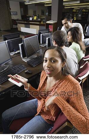 Portrait of a smiling woman sitting with friends while using computers in the library View Large Photo Image Stock Photograph - Portrait of a smiling woman sitting with friends while using computers in the library. Fotosearch