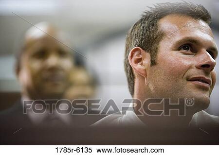 Stock Photography - Portrait of a smiling young businessman with his colleagues in the background. Fotosearch