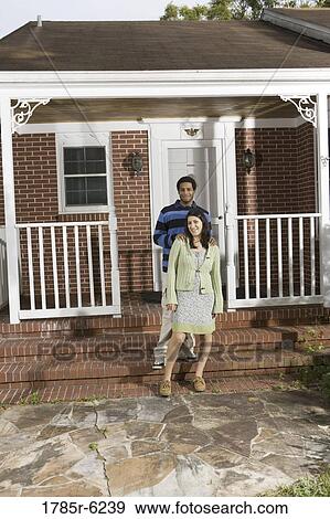 Stock Photo - Portrait of a smiling young interracial couple on front steps house. Fotosearch