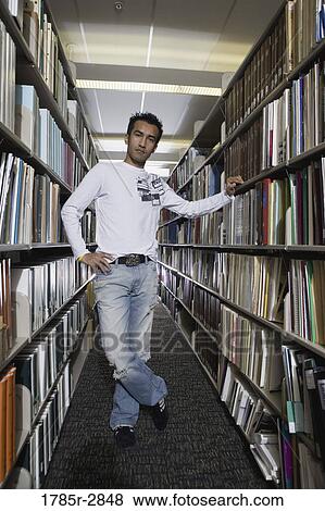 Portrait of a student standing in the library amidst book stacks View Large Photo Image Stock Photo - Portrait of a student standing in the library amidst book stacks. Fotosearch