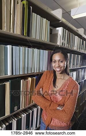 Portrait of a student standing in the library amidst book stacks View Large Photo Image Stock Photograph - Portrait of a student standing in the library amidst book stacks. Fotosearch