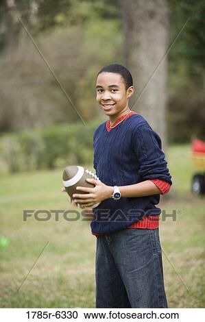 Stock Image - Portrait of a teenage boy holding a football. Fotosearch