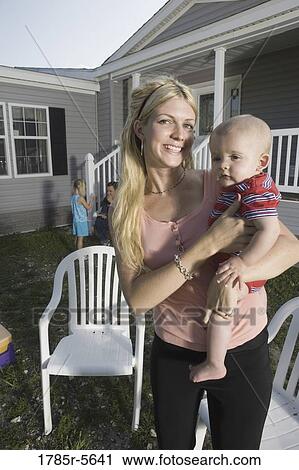 Portrait of a woman holding a baby in front of a trailer home View Large Photo Image Stock Image - Portrait of a woman holding a baby in front of a trailer home. Fotosearch