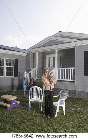 Portrait of a woman holding a baby in front of a trailer home View Large Photo Image Stock Image - Portrait of a woman holding a baby in front of a trailer home. Fotosearch