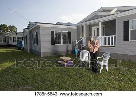 Portrait of a woman holding a baby in front of a trailer home View Large Photo Image Stock Image - Portrait of a woman holding a baby in front of a trailer home. Fotosearch