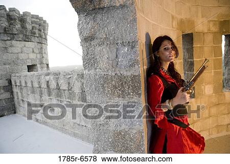 Portrait of a woman pirate armed with a pistol standing inside a castle turret View Large Photo Image Stock Photo - Portrait of a woman pirate armed with a pistol standing inside a castle turret. Fotosearch