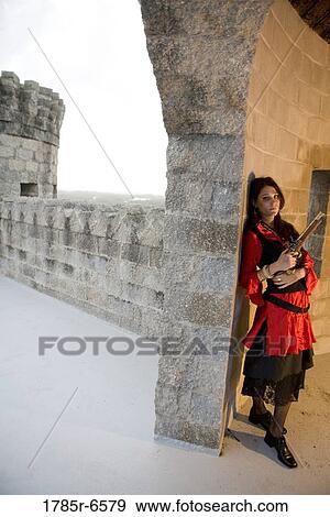Portrait of a woman pirate armed with a pistol standing inside a castle turret View Large Photo Image Stock Photo - Portrait of a woman pirate armed with a pistol standing inside a castle turret. Fotosearch