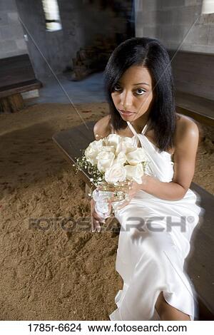 Picture - Portrait of a young bride in a white gown holding a bouquet of white roses inside a medieval castle. Fotosearch