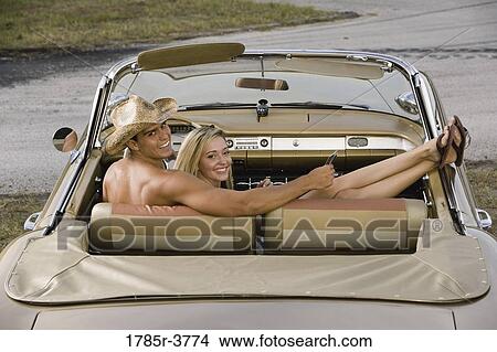 Portrait of a young couple sitting in antique convertible car View Large Photo Image Picture - Portrait of a young couple sitting in antique convertible car. Fotosearch