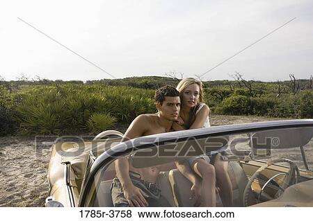 Stock Photo - Portrait of a young couple sitting in antique convertible car. Fotosearch