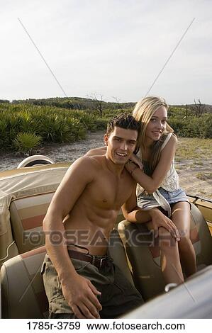 Stock Photo - Portrait of a young couple sitting in antique convertible car. Fotosearch