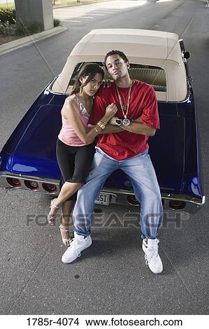 Portrait of a young hip-hop couple standing beside a pimped-up vintage car View Large Photo Image Picture - Portrait of a young hip-hop couple standing beside a pimped-up vintage car. Fotosearch