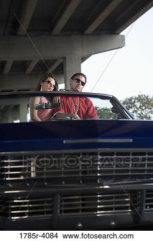 Portrait of a young hip-hop couple sitting in a pimped-up vintage car under a highway overpass View Large Photo Image Picture - Portrait of a young hip-hop couple sitting in a pimped-up vintage car under a highway overpass. Fotosearch