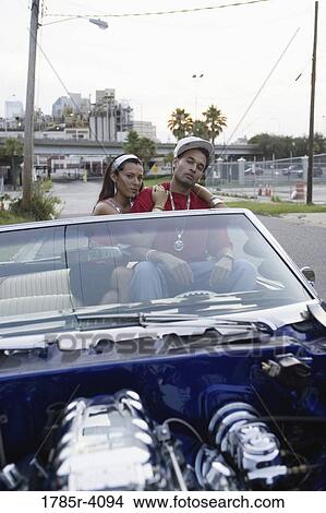 Portrait of a young hip-hop couple sitting in a pimped-up vintage car in urban neighborhood View Large Photo Image Picture - Portrait of a young hip-hop couple sitting in a pimped-up vintage car in urban neighborhood. Fotosearch
