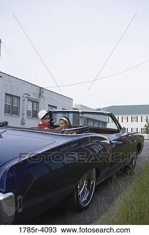 Portrait of a young hip-hop couple sitting in a pimped-up vintage car in urban neighborhood View Large Photo Image Stock Image - Portrait of a young hip-hop couple sitting in a pimped-up vintage car in urban neighborhood. Fotosearch