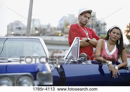 Portrait of a young hip-hop couple standing beside a convertible View Large Photo Image Stock Image - Portrait of a young hip-hop couple standing beside a convertible. Fotosearch