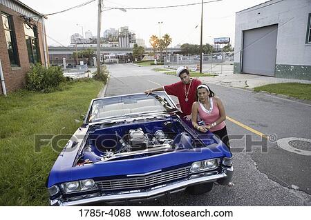 Portrait of a young hip-hop couple standing beside a pimped-up vintage car in depressed urban neighborhood View Large Photo Image Stock Photo - Portrait of a young hip-hop couple standing beside a pimped-up vintage car in depressed urban neighborhood. Fotosearch