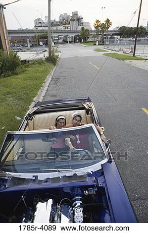 Portrait of a young hip-hop couple sitting in a pimped-up vintage car in depressed urban neighborhood View Large Photo Image Stock Photo - Portrait of a young hip-hop couple sitting in a pimped-up vintage car in depressed urban neighborhood. Fotosearch
