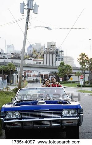 Portrait of a young hip-hop couple sitting in a pimped-up vintage car in depressed urban neighborhood View Large Photo Image Stock Photo - Portrait of a young hip-hop couple sitting in a pimped-up vintage car in depressed urban neighborhood. Fotosearch