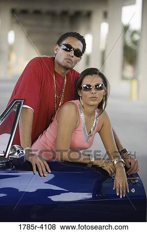 Stock Photo - Portrait of a young hip-hop couple standing beside a pimped-up vintage car under a highway overpass. Fotosearch