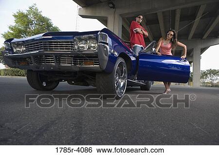 Portrait of a young hip-hop couple standing beside a pimped-up vintage car under a highway overpass View Large Photo Image Stock Photograph - Portrait of a young hip-hop couple standing beside a pimped-up vintage car under a highway overpass. Fotosearch