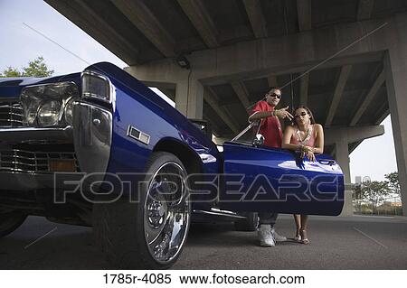 Portrait of a young hip-hop couple standing beside a pimped-up vintage car under a highway overpass View Large Photo Image Stock Photography - Portrait of a young hip-hop couple standing beside a pimped-up vintage car under a highway overpass. Fotosearch