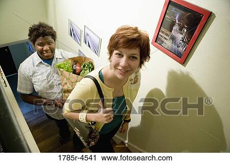 Portrait of a young inter-racial couple carrying groceries upstairs View Large Photo Image Stock Image - Portrait of a young inter-racial couple carrying groceries upstairs. Fotosearch