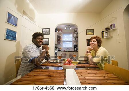 Portrait of a young inter-racial couple sitting at dining table View Large Photo Image Stock Photo - Portrait of a young inter-racial couple sitting at dining table. Fotosearch