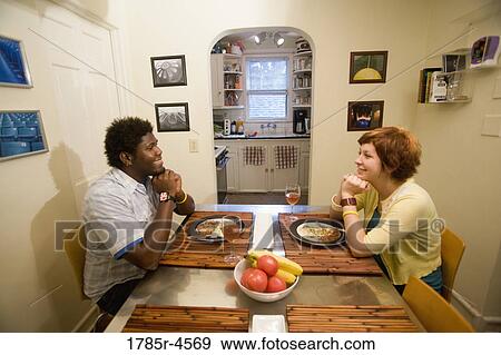 Portrait of a young inter-racial couple sitting at dining table View Large Photo Image Stock Photo - Portrait of a young inter-racial couple sitting at dining table. Fotosearch