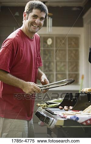 Portrait of a young man holding tongs cooking at an outdoor grill View Large Photo Image Stock Photography - Portrait of a young man holding tongs cooking at an outdoor grill. Fotosearch