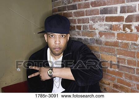 Portrait of a young man in hip-hop fashion sitting against brick wall View Large Photo Image Stock Image - Portrait of a young man in hip-hop fashion sitting against brick wall. Fotosearch