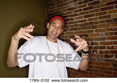 Portrait of a young man in hip-hop fashion standing against brick wall and showing gangsta hand gestures View Large Photo Image Stock Image - Portrait of a young man in hip-hop fashion standing against brick wall and showing gangsta hand gestures. Fotosearch