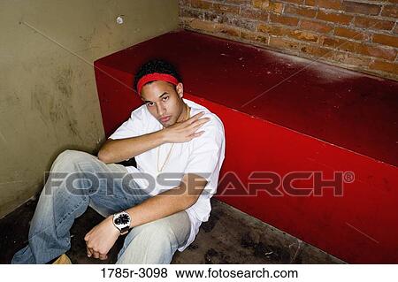 Portrait of a young man in hip-hop fashion sitting on the floor View Large Photo Image Stock Photo - Portrait of a young man in hip-hop fashion sitting on the floor. Fotosearch