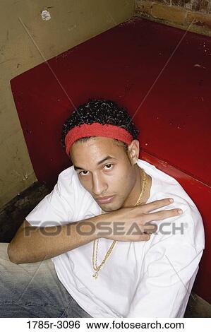 Portrait of a young man in hip-hop fashion sitting on the floor View Large Photo Image Stock Photograph - Portrait of a young man in hip-hop fashion sitting on the floor. Fotosearch