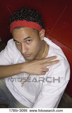 Stock Photography - Portrait of a young man in hip-hop fashion sitting on the floor. Fotosearch