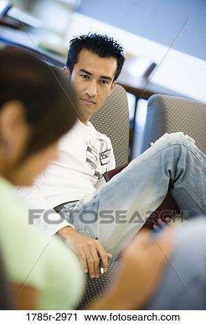 Portrait of a young man sitting on the sofa View Large Photo Image Stock Image - Portrait of a young man sitting on the sofa. Fotosearch