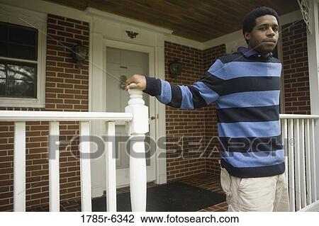 Portrait of a young man standing on front porch of house View Large Photo Image Stock Image - Portrait of a young man standing on front porch of house. Fotosearch