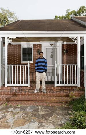 Portrait of a young man standing on front porch of house View Large Photo Image Stock Photo - Portrait of a young man standing on front porch of house. Fotosearch