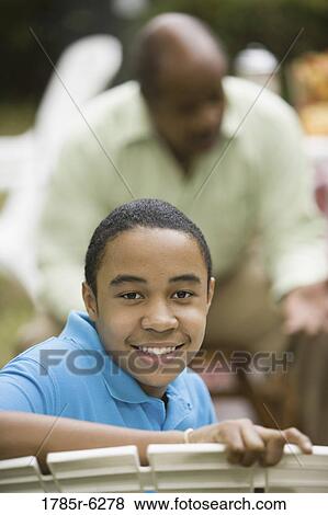 Stock Photo - Portrait of African boy smiling with father in background. Fotosearch
