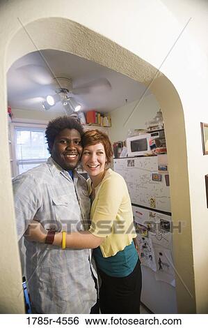 Portrait of an affectionate young inter-racial couple outside kitchen View Large Photo Image Stock Photograph - Portrait of an affectionate young inter-racial couple outside kitchen. Fotosearch